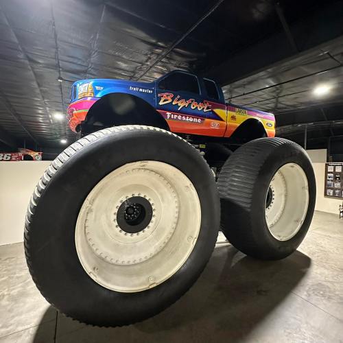 A large monster truck named Bigfoot displayed on oversized tires in a dimly lit indoor space.