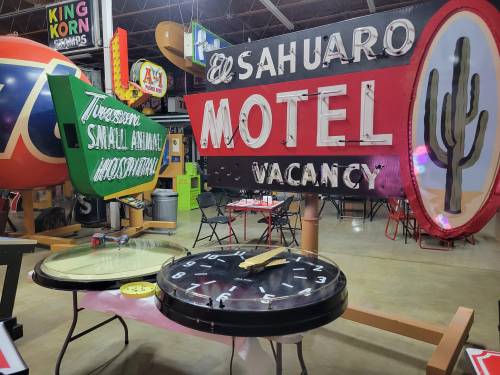 Colorful vintage signs, including a cactus and a motel sign, displayed in a retro-themed setting.