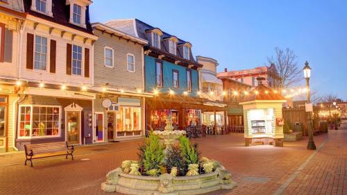 Charming street lined with colorful buildings and string lights, featuring a fountain and outdoor dining areas at dusk.