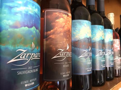 A row of wine bottles with colorful labels, featuring Zarpan branding and various wine types from 2022.