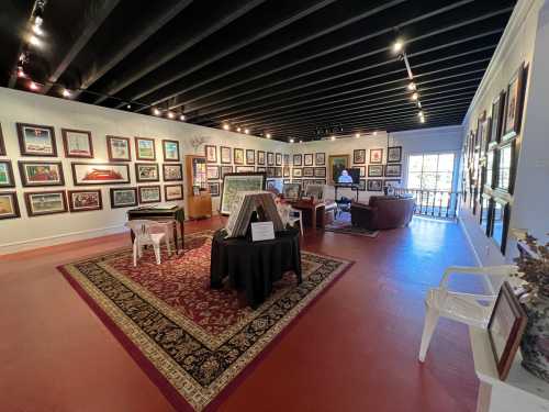 Art gallery interior featuring framed artworks on walls, a central display table, and seating areas.