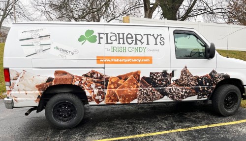 A white van with a colorful candy-themed wrap featuring Flaherty's Irish Candy Company logo and website.