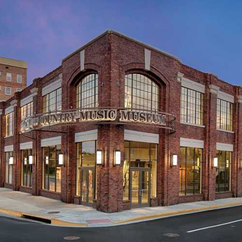 Exterior view of the Country Music Museum, featuring a brick facade and large windows at dusk.