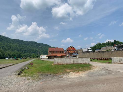 A small town scene featuring a building with a sign, surrounded by green hills and a gravel road.