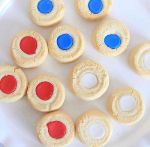 A plate of round cookies with colored icing in red, blue, and white, arranged in a neat pattern.