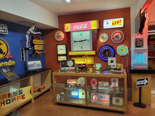 A display of vintage signs, clocks, and neon lights in a colorful exhibit showcasing nostalgic memorabilia.