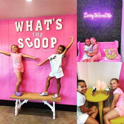 Two girls pose joyfully in a pink-themed ice cream shop, enjoying treats and a fun atmosphere.