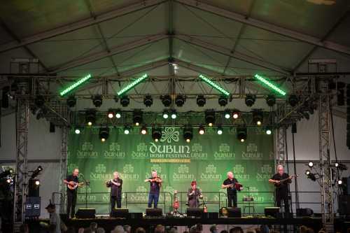 A band performs on stage at the Dublin Irish Festival, with green lights and a festive backdrop.