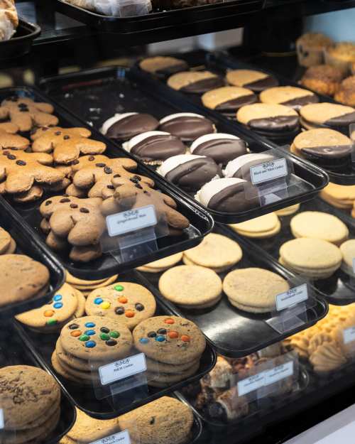 A display case filled with various cookies, including chocolate chip, sandwich cookies, and iced treats.