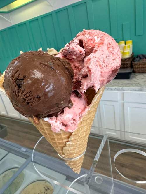 A waffle cone filled with two scoops of ice cream: one chocolate and one strawberry.