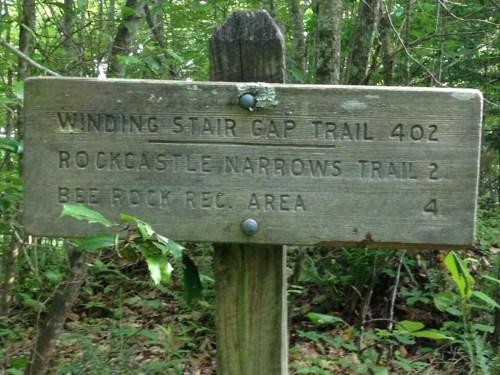 Wooden trail sign indicating distances to Winding Stair Gap Trail, Rockcastle Narrows Trail, and Bee Rock Recreation Area.