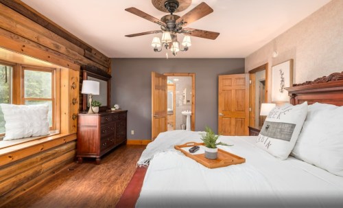 Cozy bedroom with wooden accents, a large bed, and a view of a bathroom through an open door.