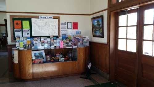 Information desk with brochures and maps, wooden walls, and a door leading outside.