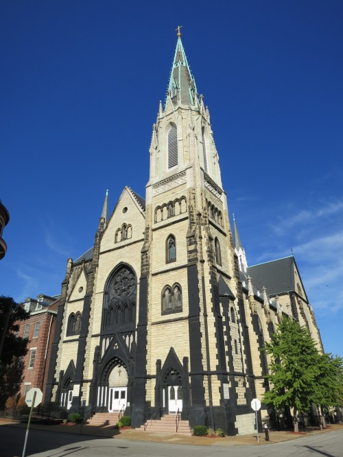A tall church with a pointed steeple, intricate stonework, and a clear blue sky in the background.