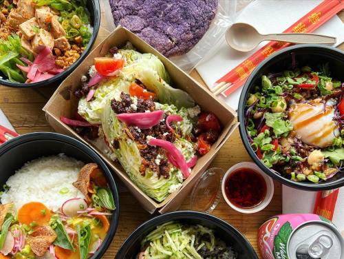 A variety of colorful dishes including salads, rice, and a purple tortilla, arranged on a wooden table.