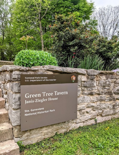 Sign for Green Tree Tavern, Janis-Ziegler House, at Ste. Genevieve National Historical Park, surrounded by greenery.