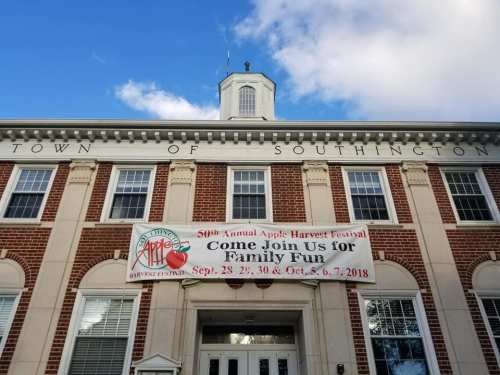Town hall building with a banner for the 50th Annual Apple Harvest Festival, inviting families to join the fun.