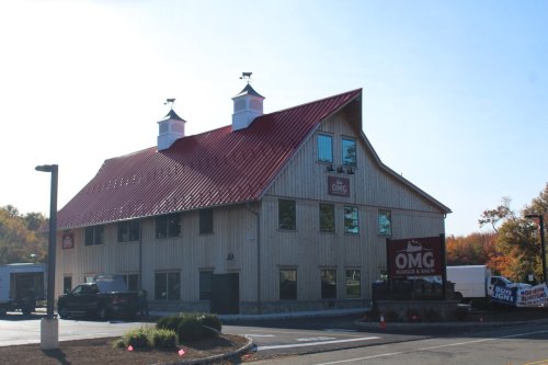 A large wooden building with a red roof, featuring signs for "OMG Burger & Brew" and surrounded by trees.