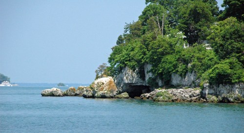 A serene coastal scene featuring lush greenery on rocky cliffs beside calm blue waters.