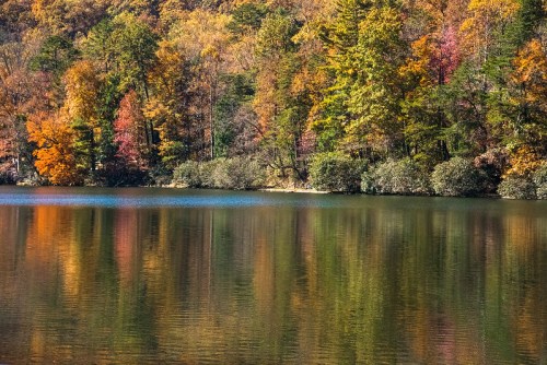 A serene lake reflecting vibrant autumn foliage in shades of orange, red, and green.