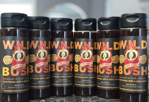 Six bottles of "Wild Bush" honey, featuring a bold label with a spicy theme, arranged in a row on a countertop.