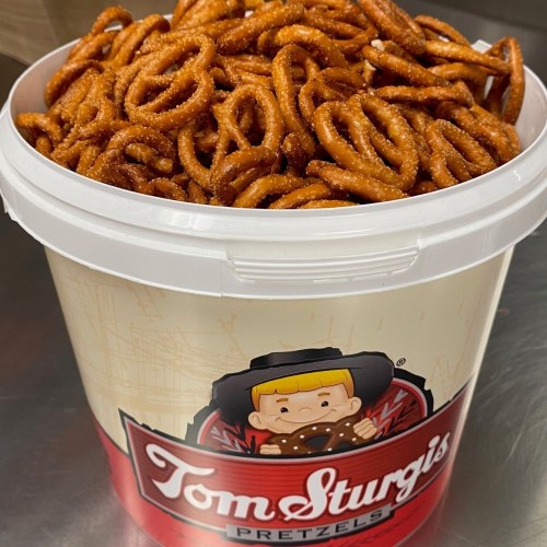 A large white bucket filled with crunchy pretzels, labeled "Tom Sturgis Pretzels."