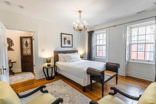 Cozy bedroom with a double bed, two windows, a chandelier, and vintage-style furniture.