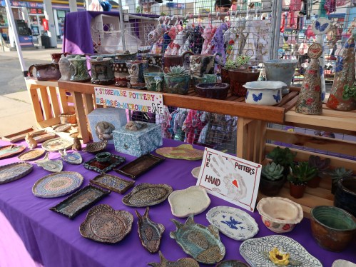 A colorful display of handmade pottery and ceramics on a table, featuring various bowls, plates, and decorative items.
