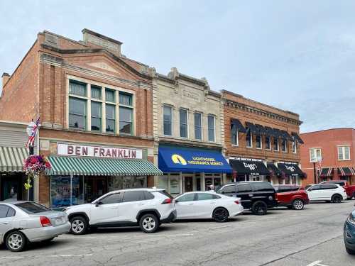 Historic buildings line a street, featuring shops like "Ben Franklin" and "Ziggy's," with parked cars in front.