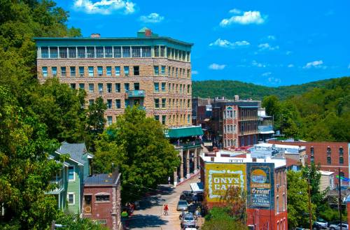 A scenic view of a historic town with buildings, trees, and a blue sky, showcasing a mix of architecture and greenery.