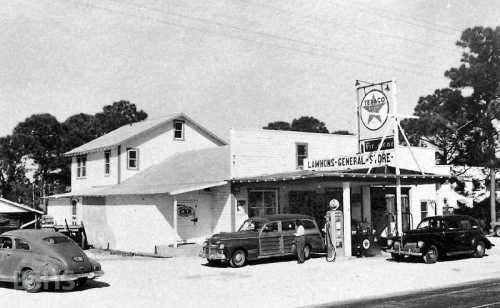Historic black-and-white photo of a general store with vintage cars and a Texaco gas station sign.
