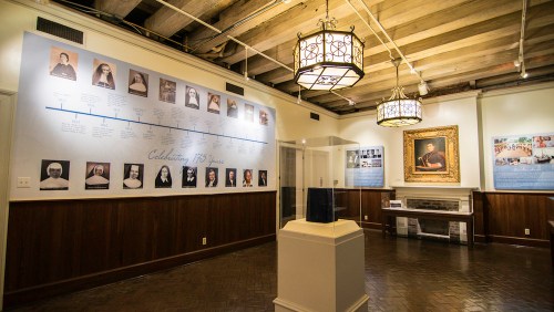 Interior of a museum exhibit featuring a timeline, portraits, and a display case, celebrating 175 years of history.