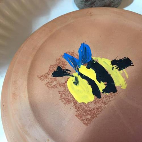 A close-up of a clay surface with abstract paint strokes in blue, yellow, and black.