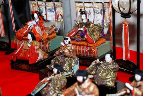 Colorful traditional Japanese dolls displayed on a red cloth, representing a ceremonial festival.