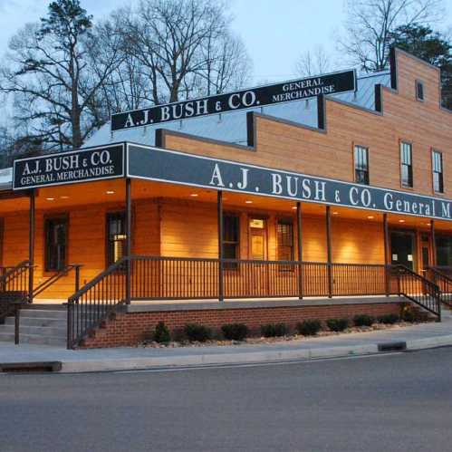 A.J. Bush & Co. General Merchandise store, a wooden building with signage, surrounded by trees and a sidewalk.