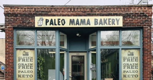 Exterior of Paleo Mama Bakery, featuring a brick facade and signs for gluten-free, grain-free, paleo, and keto options.