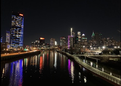 City skyline at night with illuminated buildings reflecting in the water, showcasing a vibrant urban landscape.