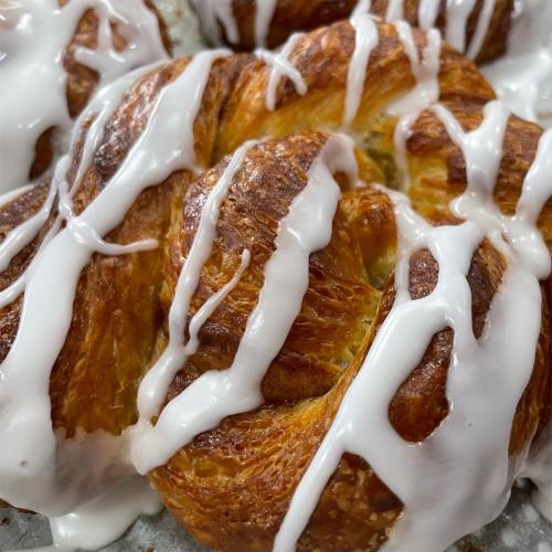 Close-up of a freshly baked cinnamon roll drizzled with white icing.