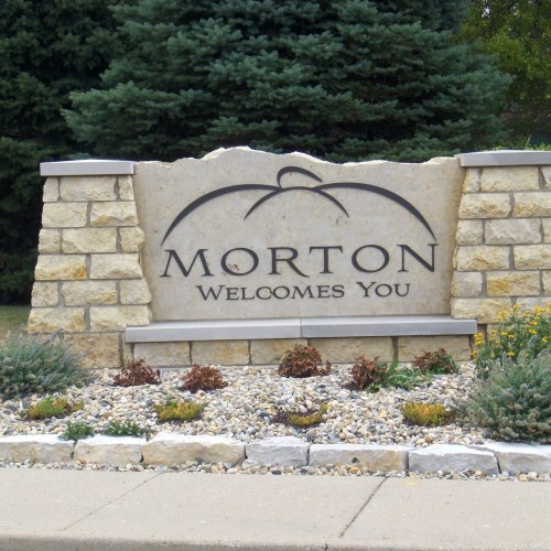 Sign reading "Morton Welcomes You" with stone and landscaping in a suburban setting.
