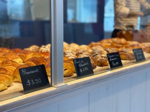 A display of various pastries, including croissants and pain au chocolat, with price tags in a bakery setting.