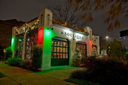 A festive building decorated with green and red lights, featuring holiday greenery and a sign that reads "Soulard."