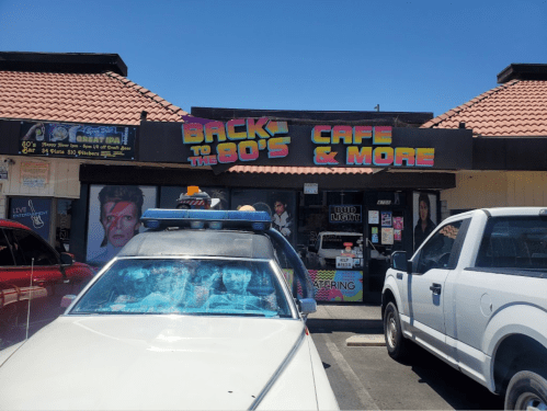 A retro-themed café called "Back to the 80's" with colorful signage and a parked car in front.