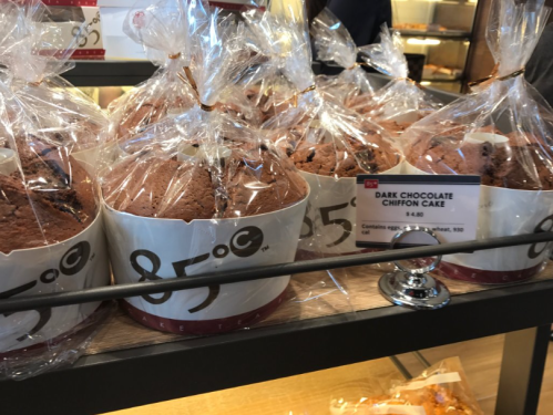 Several wrapped dark chocolate chiffon cakes displayed on a shelf, with a price tag showing $8.40.