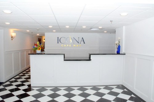Reception area of Icona Cape May, featuring a sleek desk and a checkered floor with decorative flowers.