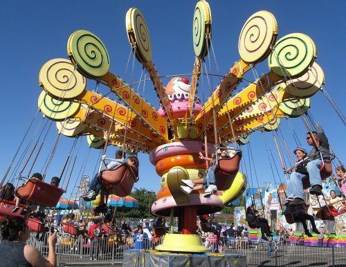 A colorful swing ride at a carnival, with children enjoying the ride against a clear blue sky.