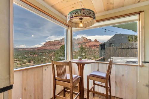 Cozy dining area with two wooden chairs, offering stunning views of red rock formations and a scenic landscape.