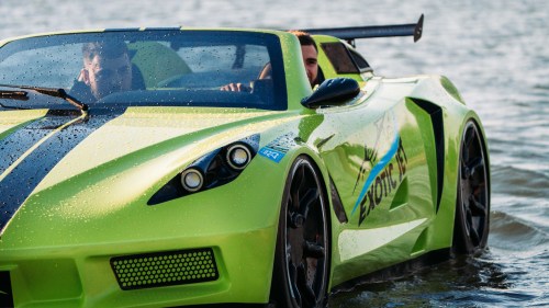 A bright green sports car partially submerged in water, with two people inside, enjoying the unique experience.
