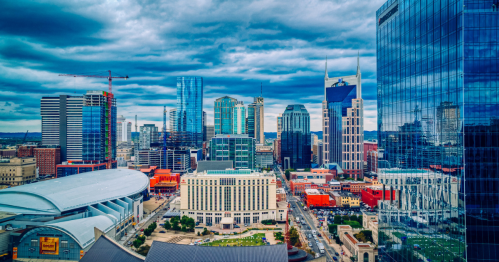 A panoramic view of a city skyline featuring modern buildings and a cloudy sky.