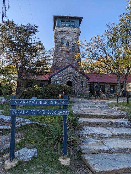 A stone tower and building at Cheaha State Park, with a sign indicating Alabama's highest point at 2,407 feet.
