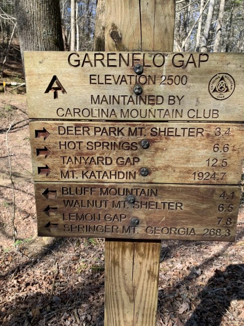 Wooden sign at Garenejo Gap, listing trail distances to various locations, including Deer Park and Mt. Katahdin.
